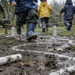 Activités extérieures enfants : enfants en tenue de pluie courent sur une piste à la craie